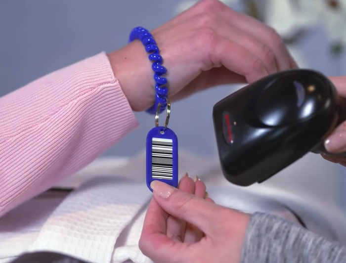 Hand holding a blue keychain label being scanned